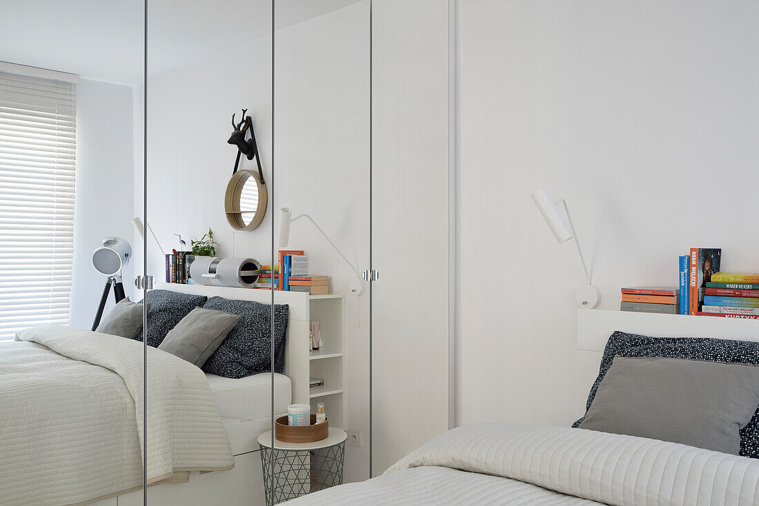 Weißes Schlafzimmer mit Regal und Spiegel in kleiner Wohnung