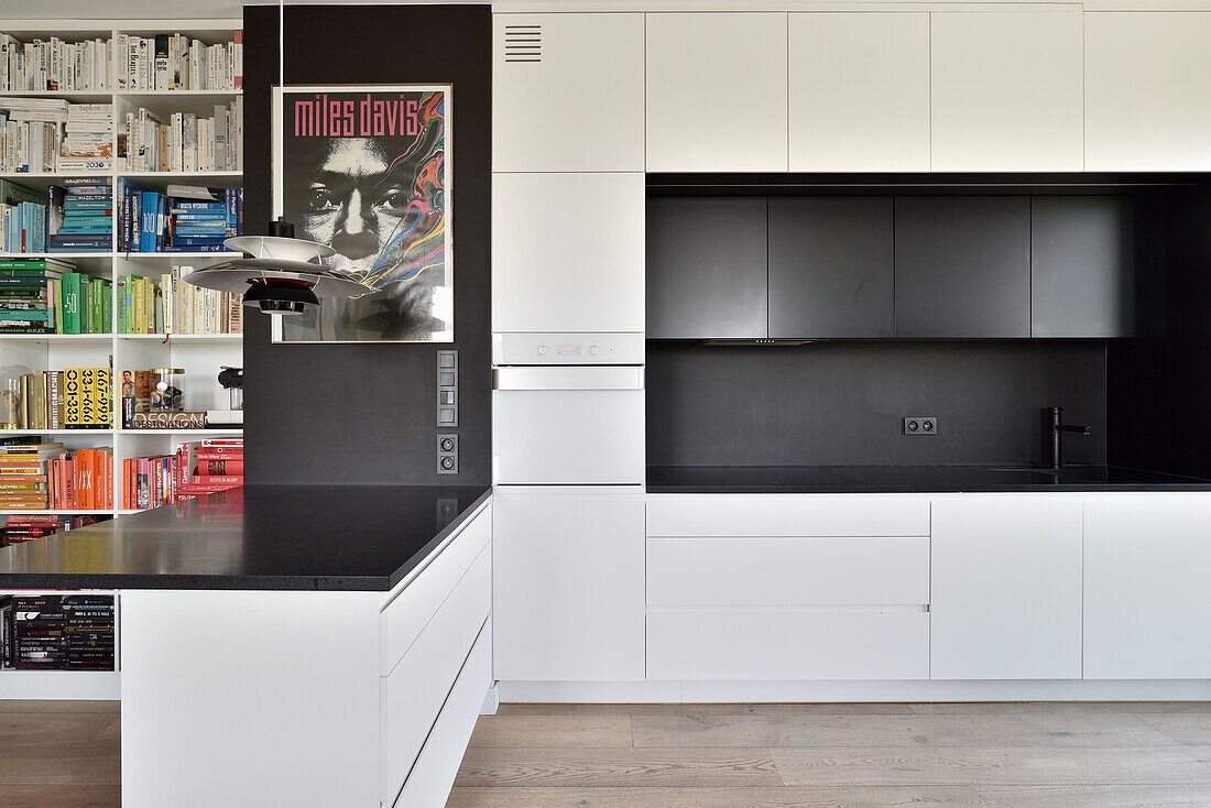 Modern kitchen in white and bookshelf in a flat in Warsaw