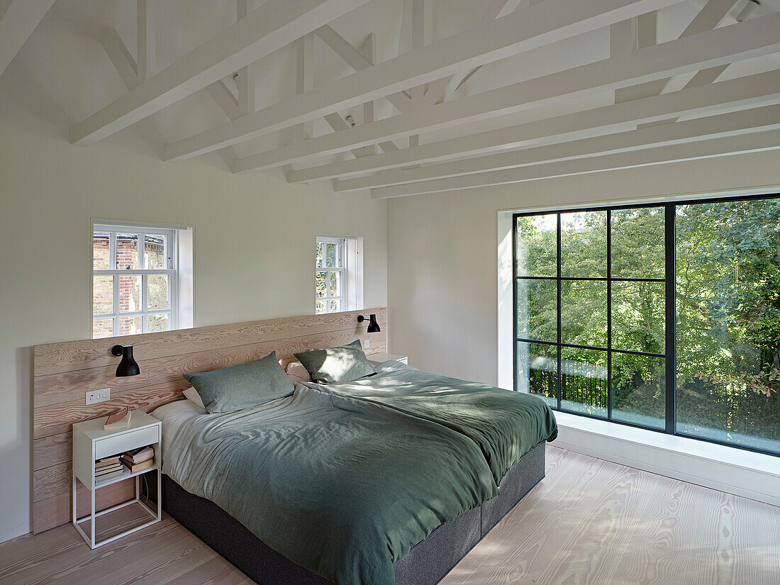 Schlafzimmer mit Doppelbett, Holzboden und Ausblick ins Grüne