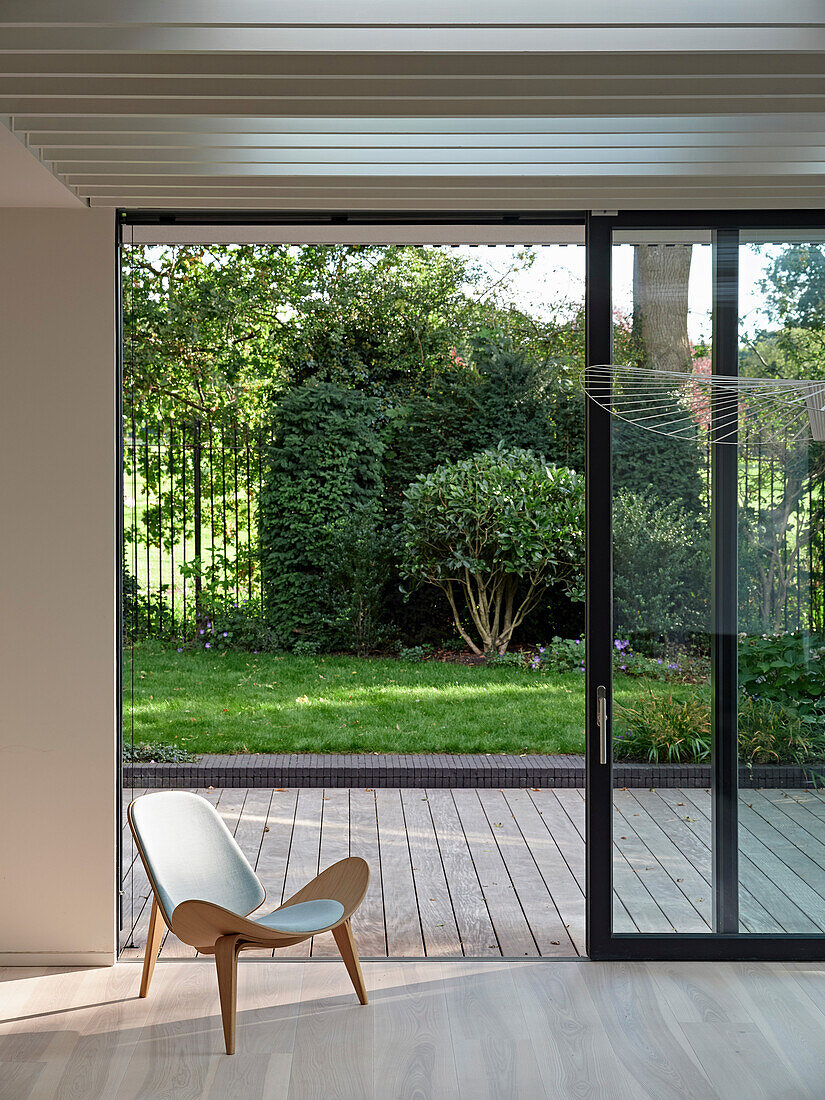 View through open sliding door to wooden terrace and yard, modern architecture