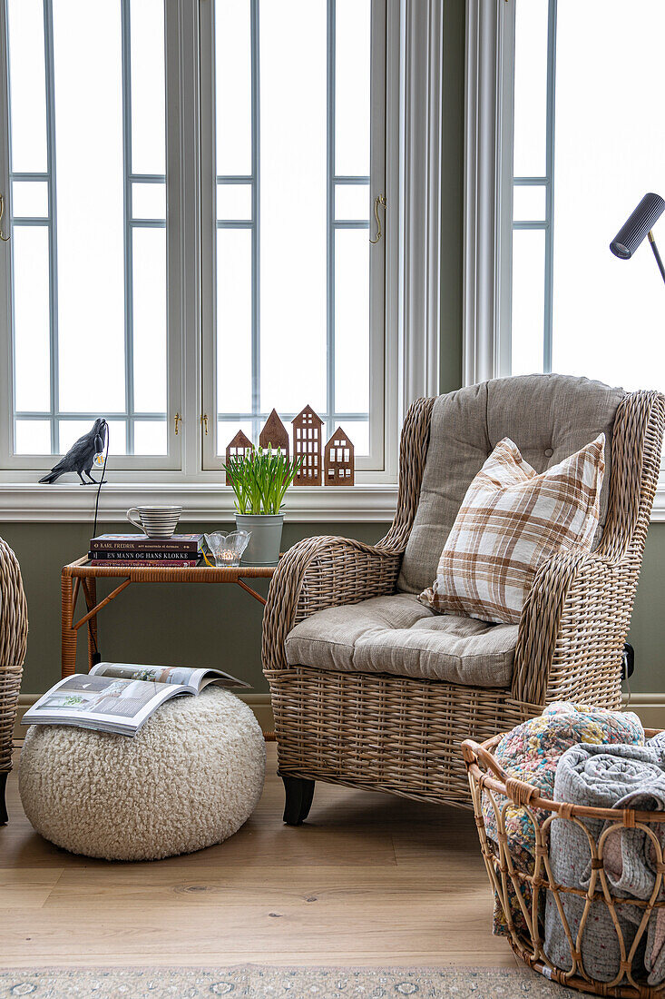 Cosy reading corner with rattan armchair and checked cushion in front of window front