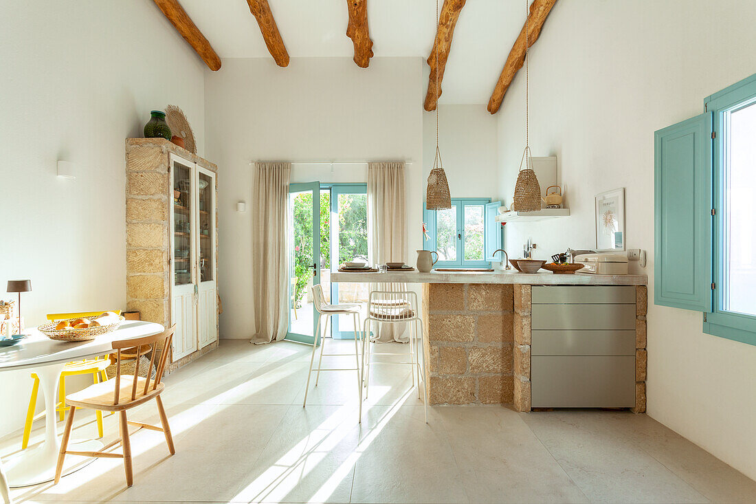 Bright kitchen with wooden beamed ceiling, natural stone counter and blue-painted window frames