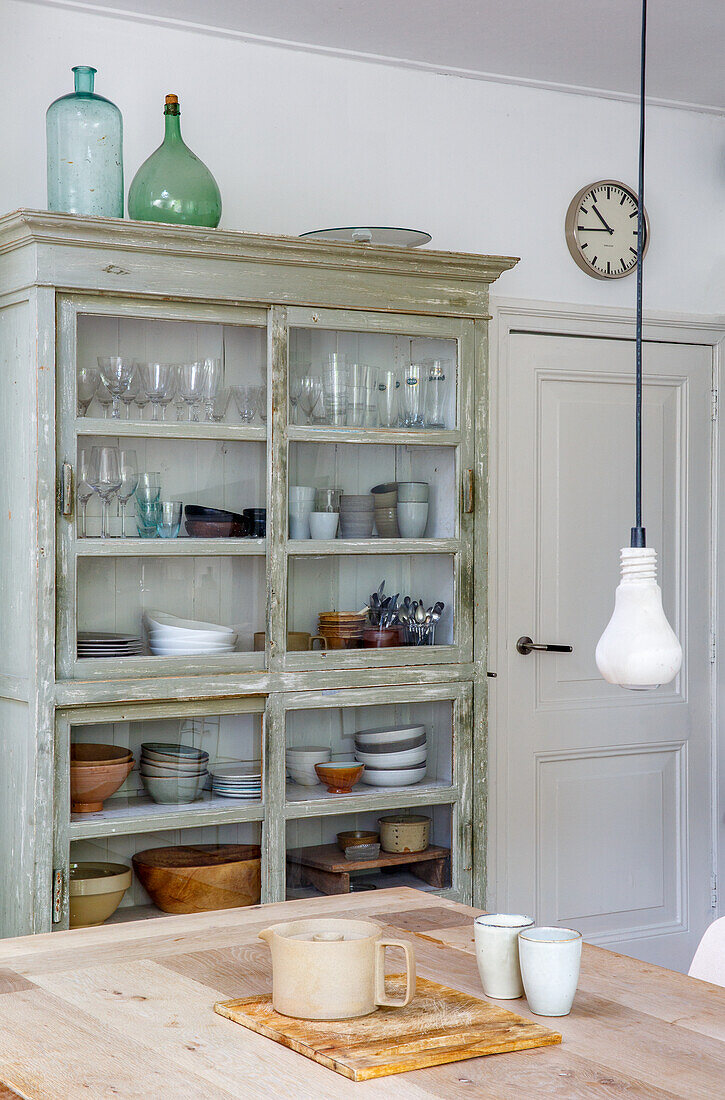 Vitrinenschrank mit Geschirr und Gläsern, Holztisch und Wanduhr