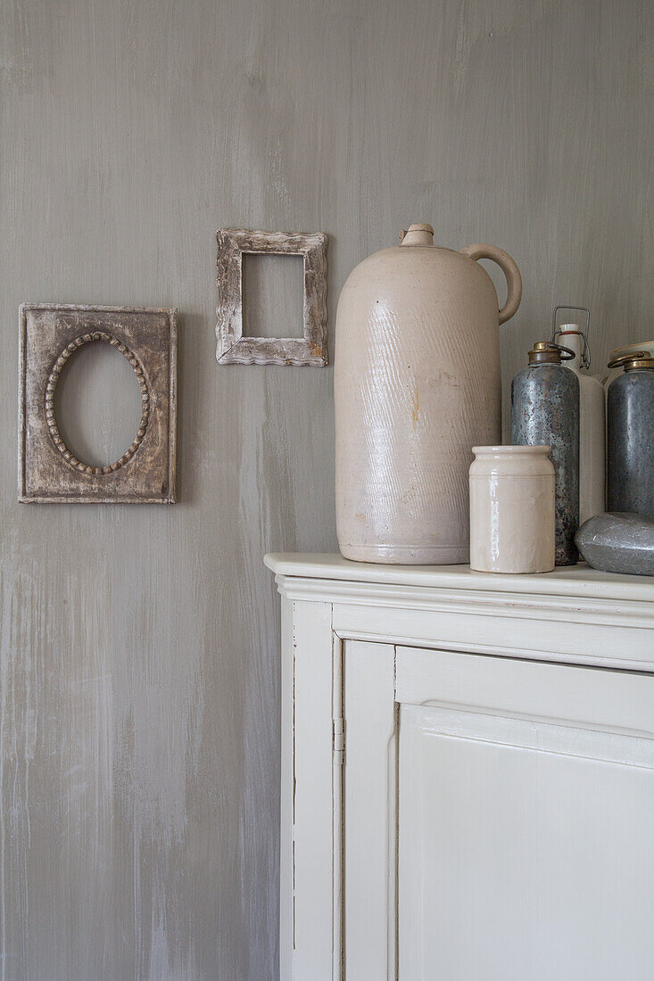 Clay pots on antique cupboard and picture frame on wall with Lemputz plaster