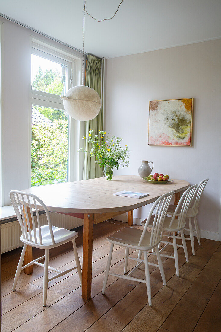 Dining area with wooden table, white chairs and bouquet of flowers