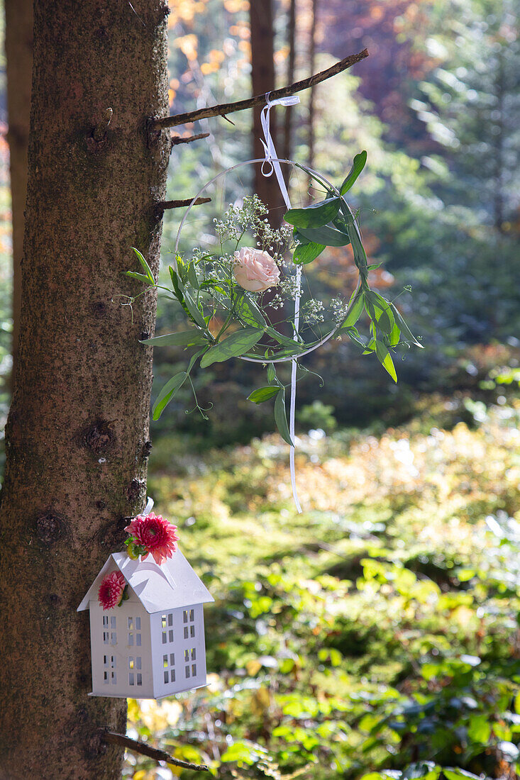 Florale Dekoration und Laterne an Baum im Wald