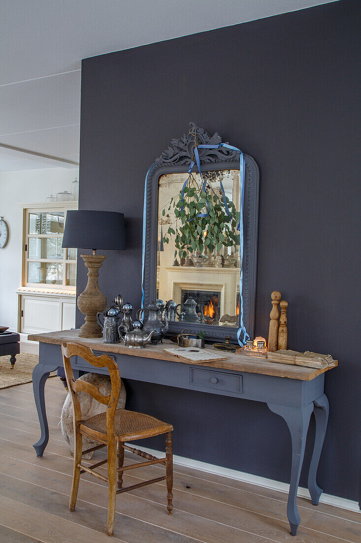 Vintage console with mirror and tea service in front of dark grey wall in the living room