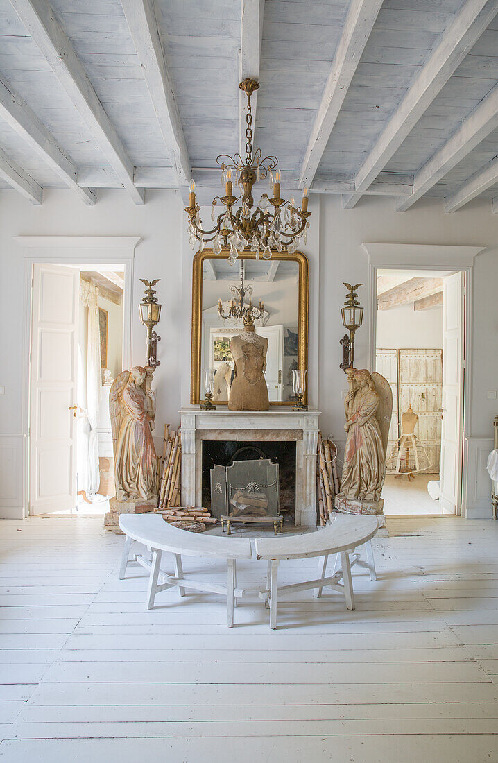 Bright living room with wooden ceiling, angel statues and benches in front of marble fireplace