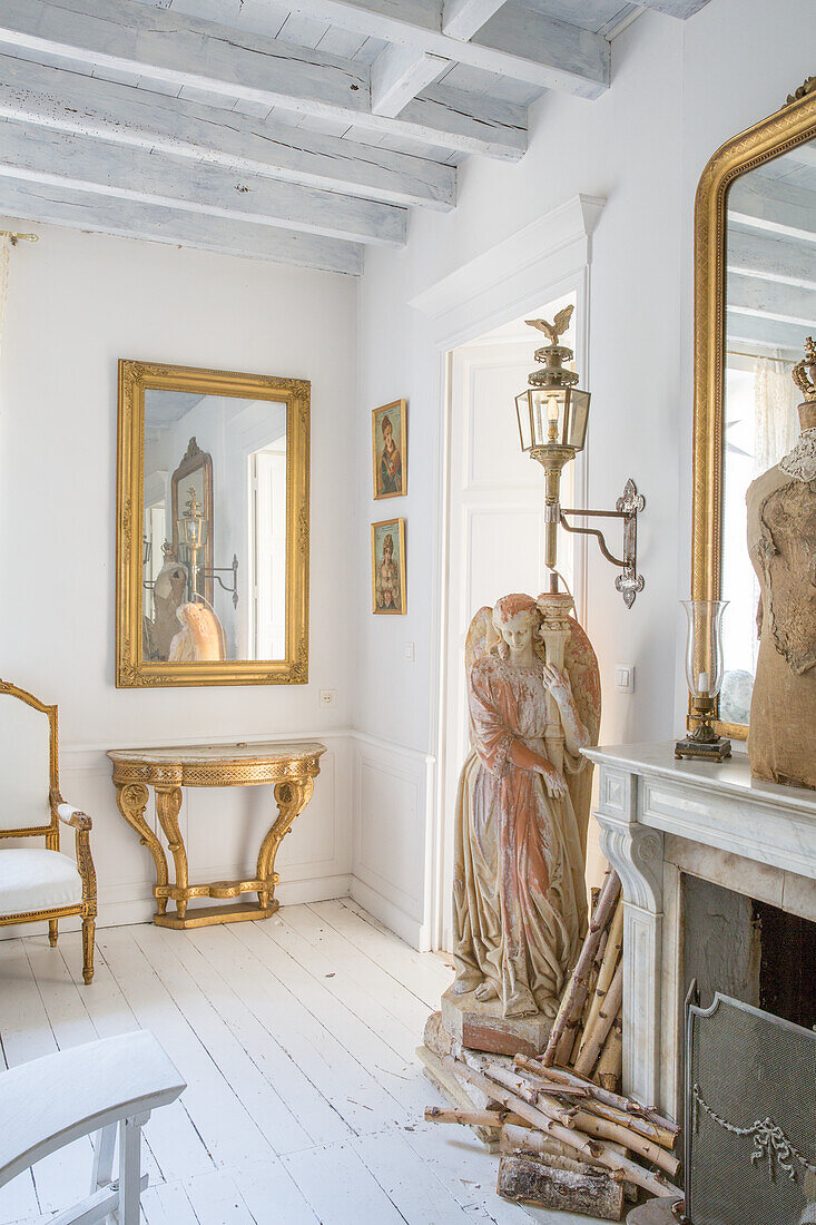 Seating area in front of open fireplace with antique furniture and angel statue