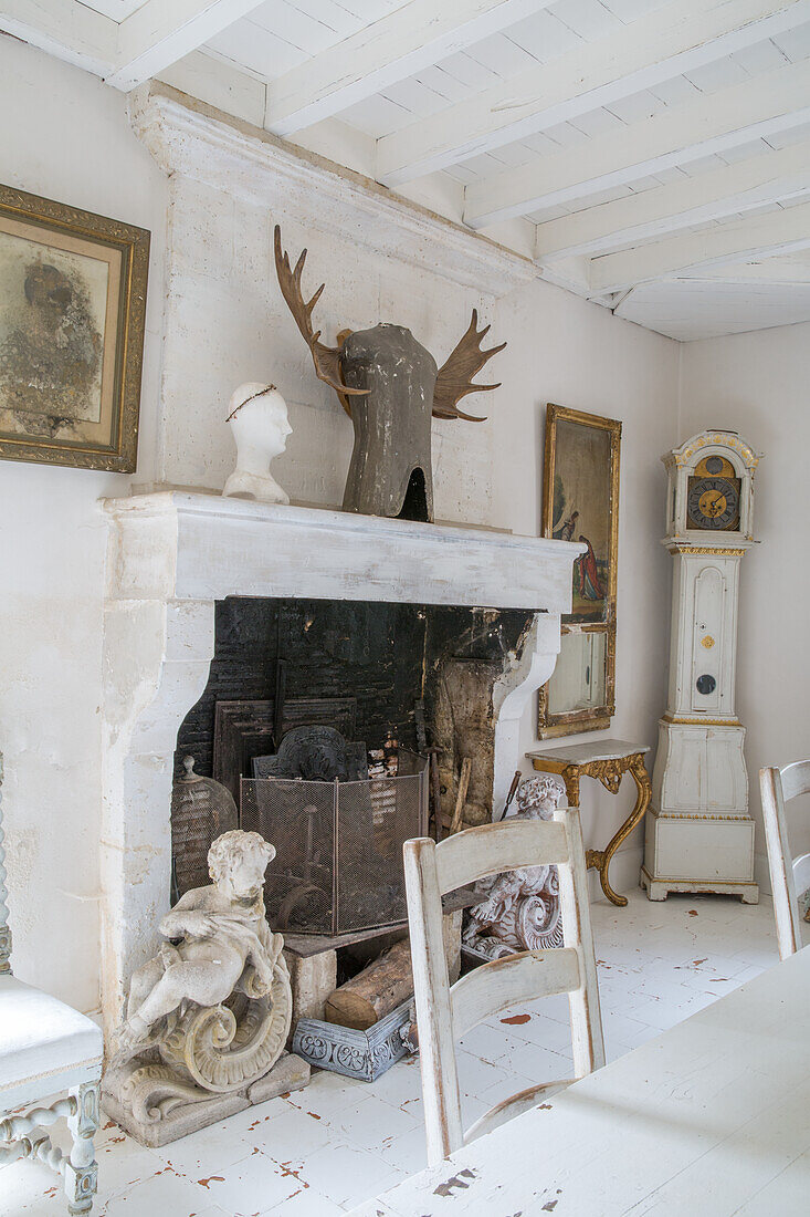 White room with country-style fireplace with statues and antique grandfather clock