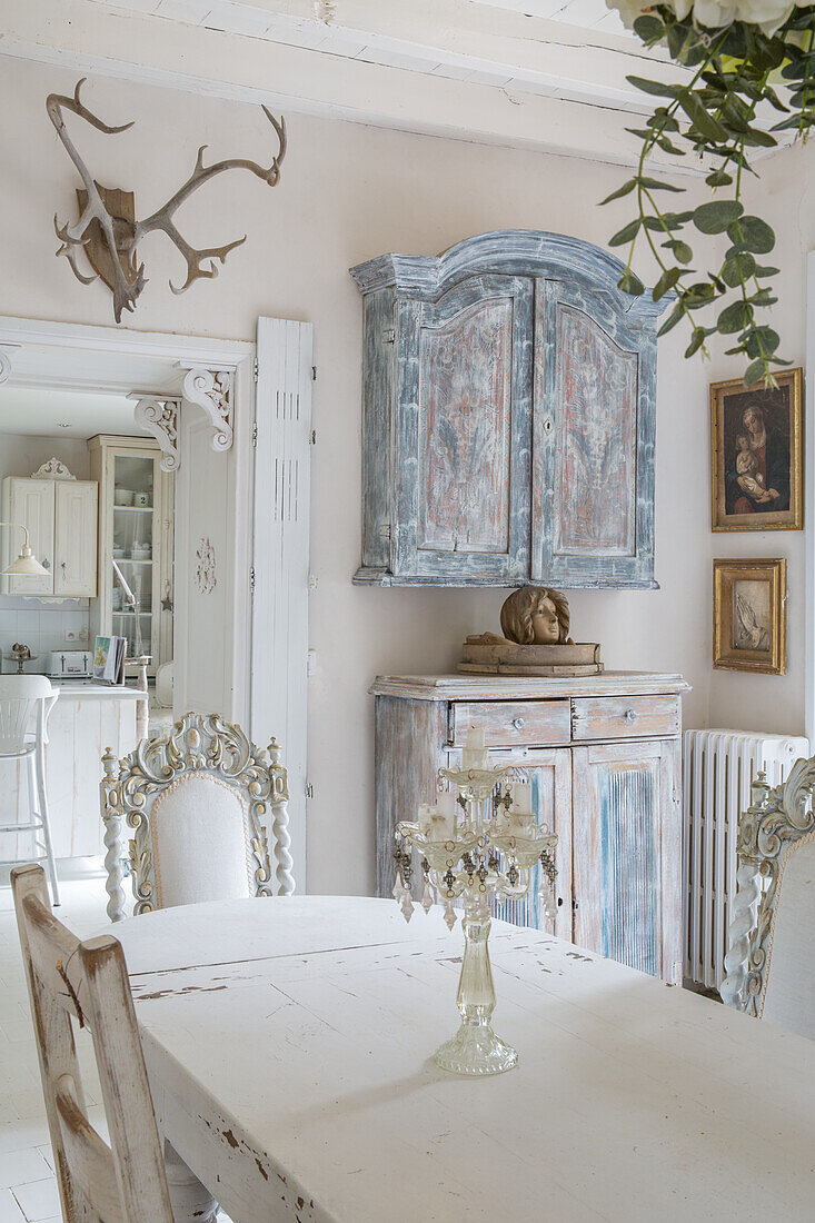 Esszimmer im Shabby-Chic-Stil mit antiken Möbeln und Hirschgeweih an der Wand