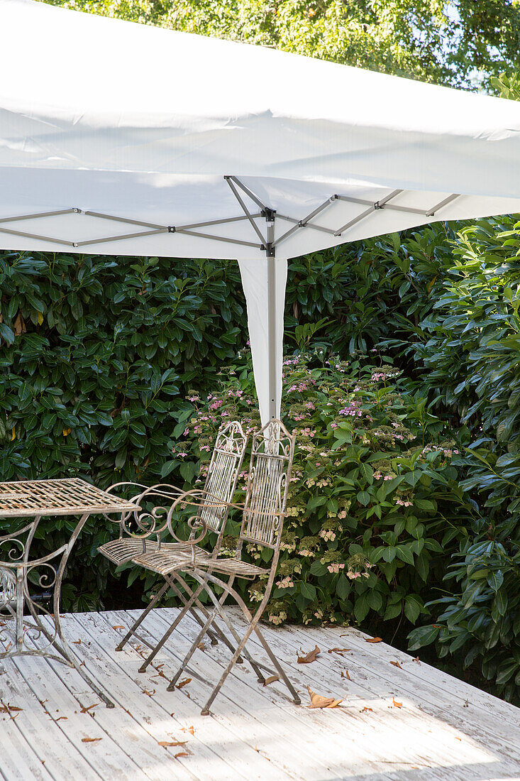 Pavilion with metal furniture on wooden terrace in the garden