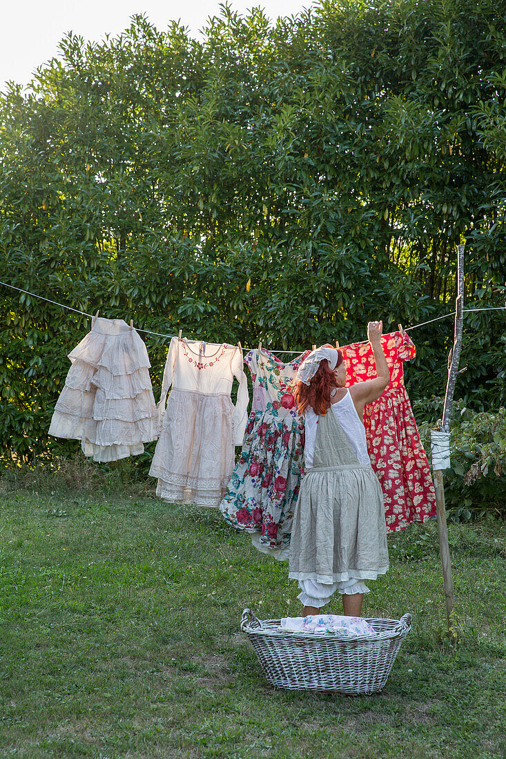 Woman hangs colourful summer dresses on a washing line in the garden