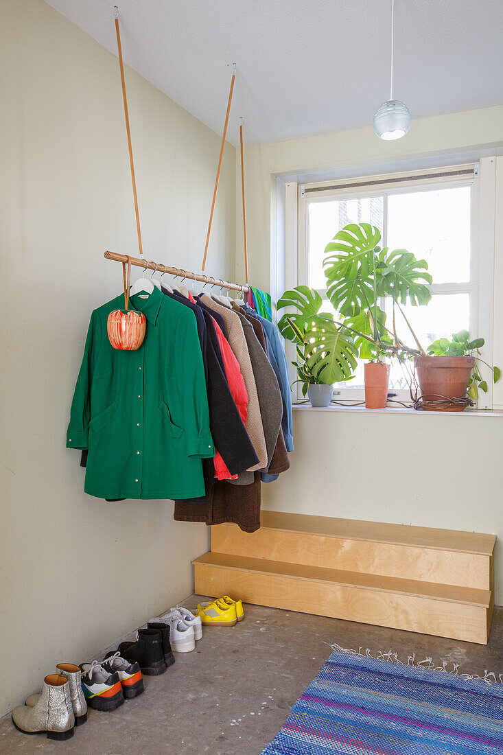 Wardrobe with floating clothes rack and monstera by the window