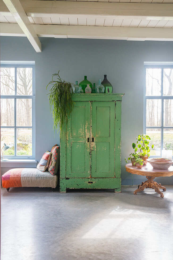 Grüner Vintage-Schrank vor blauer Wand und Steinboden