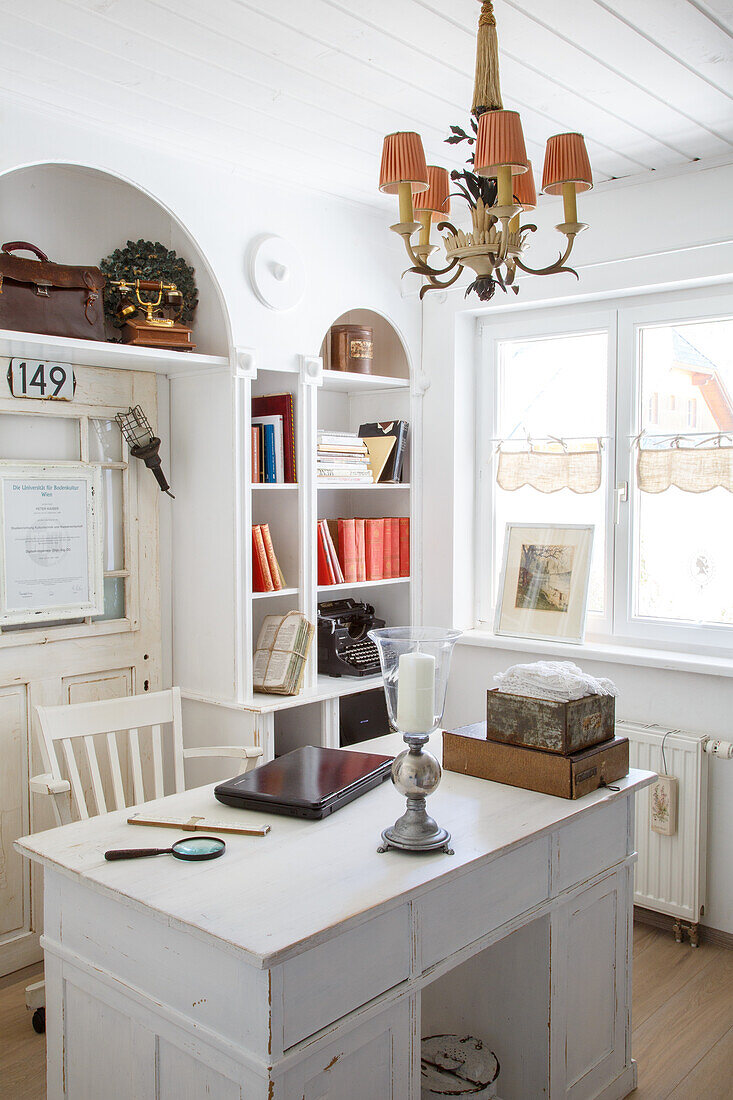 White home office with antique chandelier and open bookshelf