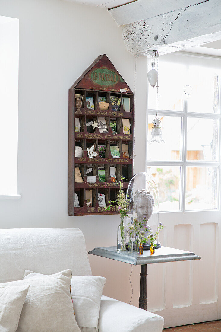 House-shaped wooden shelf with collectables and small flower vases on side table