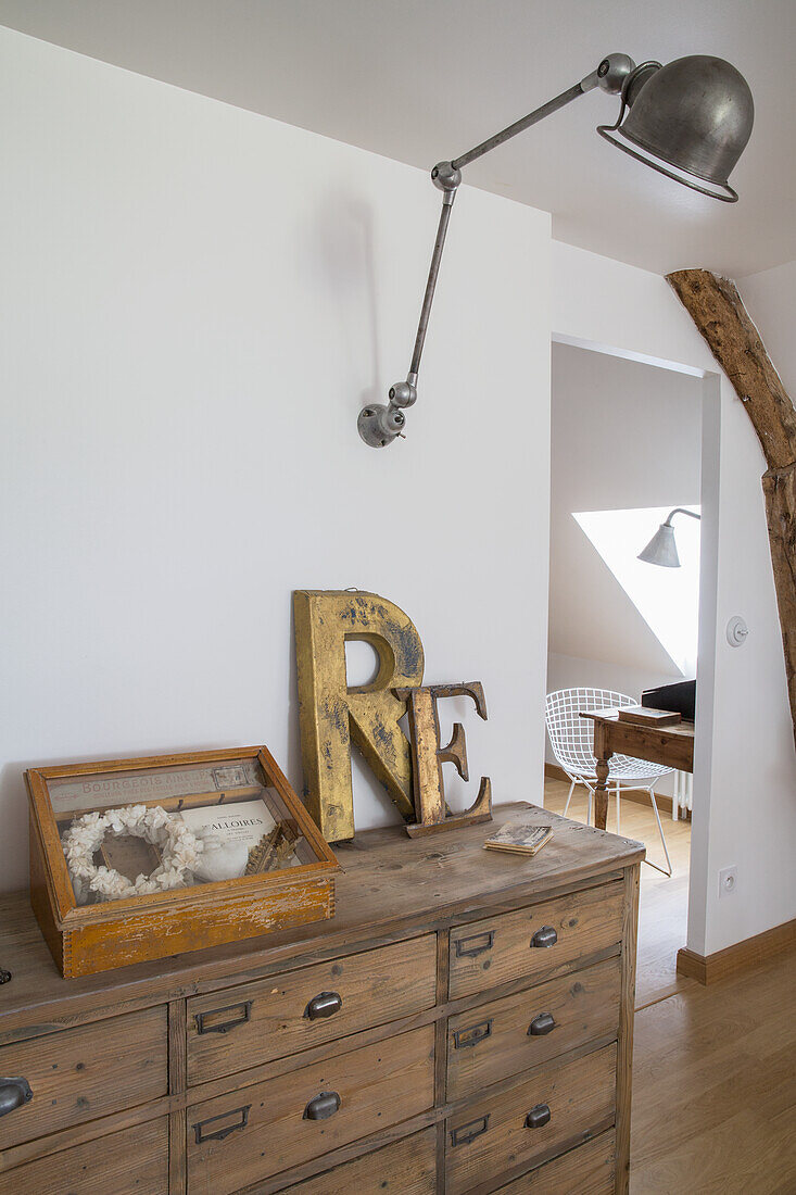 Wooden chest of drawers with metal handles, vintage decorations and wall lamp