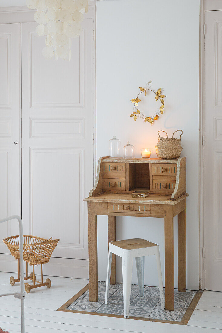 Small wooden desk with stool in a light-colored corner of the room