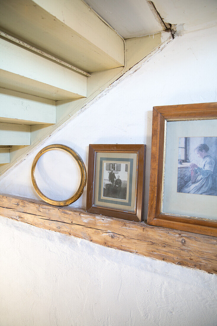 Holzbalken mit gerahmten Fotos und leerem Bilderrahmen unter Treppe