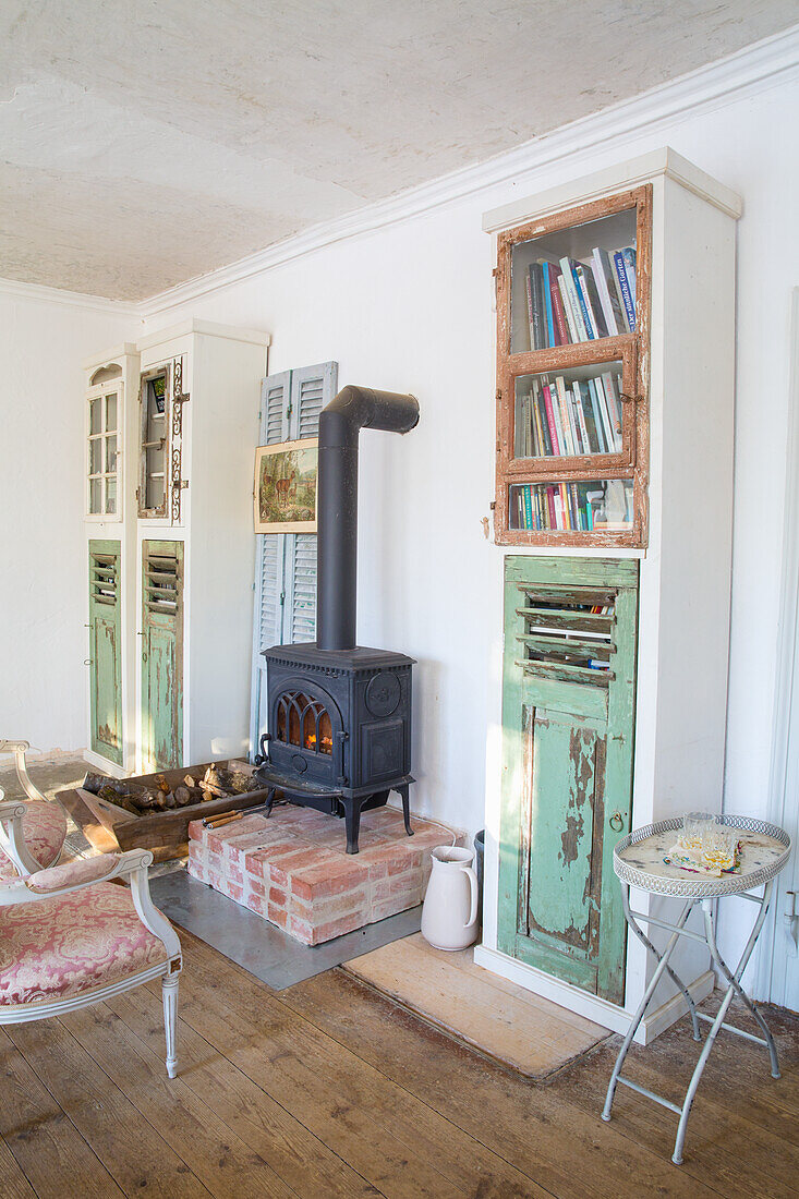 Old wood-burning stove on red clinker pedestal in rustic living room