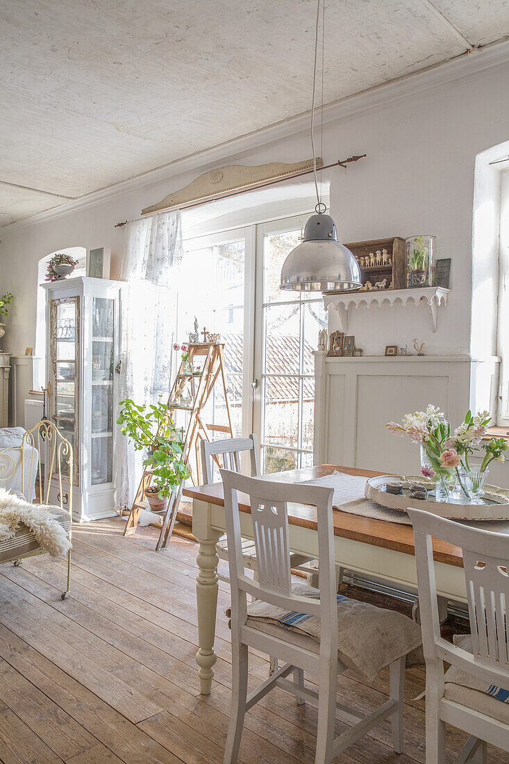 Bright dining room with wooden table, white chairs and vintage decor