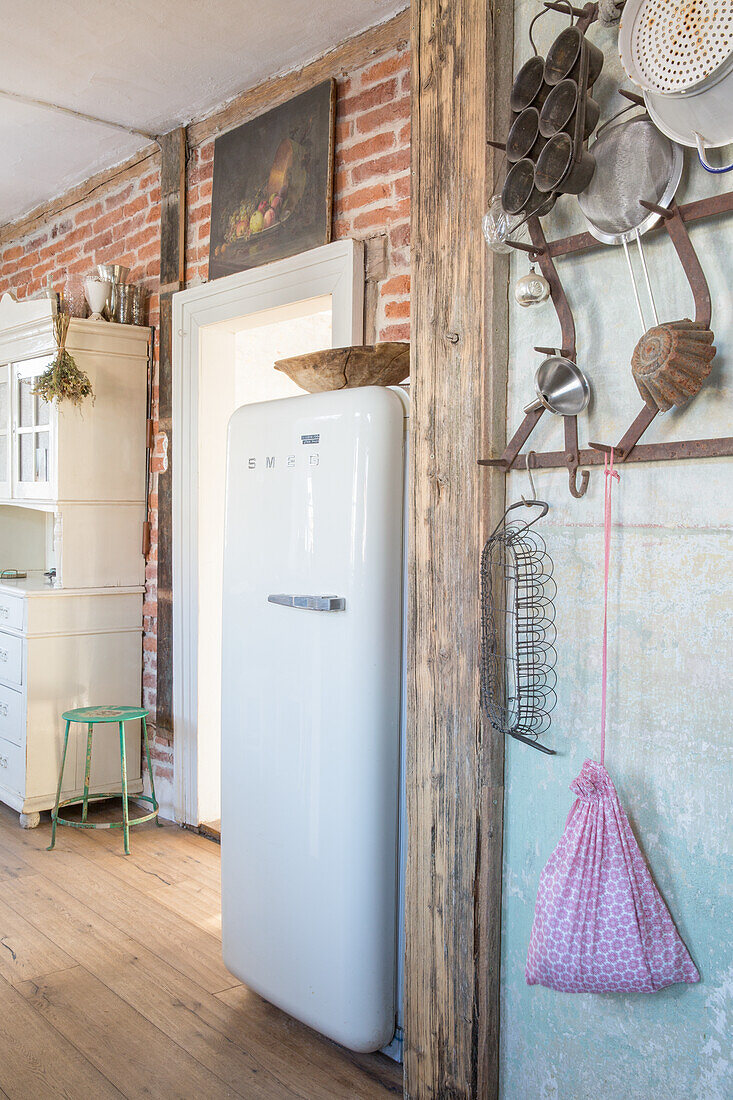 Küche mit Retro-Kühlschrank, Backsteinwand und hängendem Kochzubehör