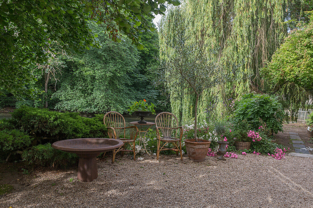 Cosy seating area with wicker furniture and round table in the shady garden