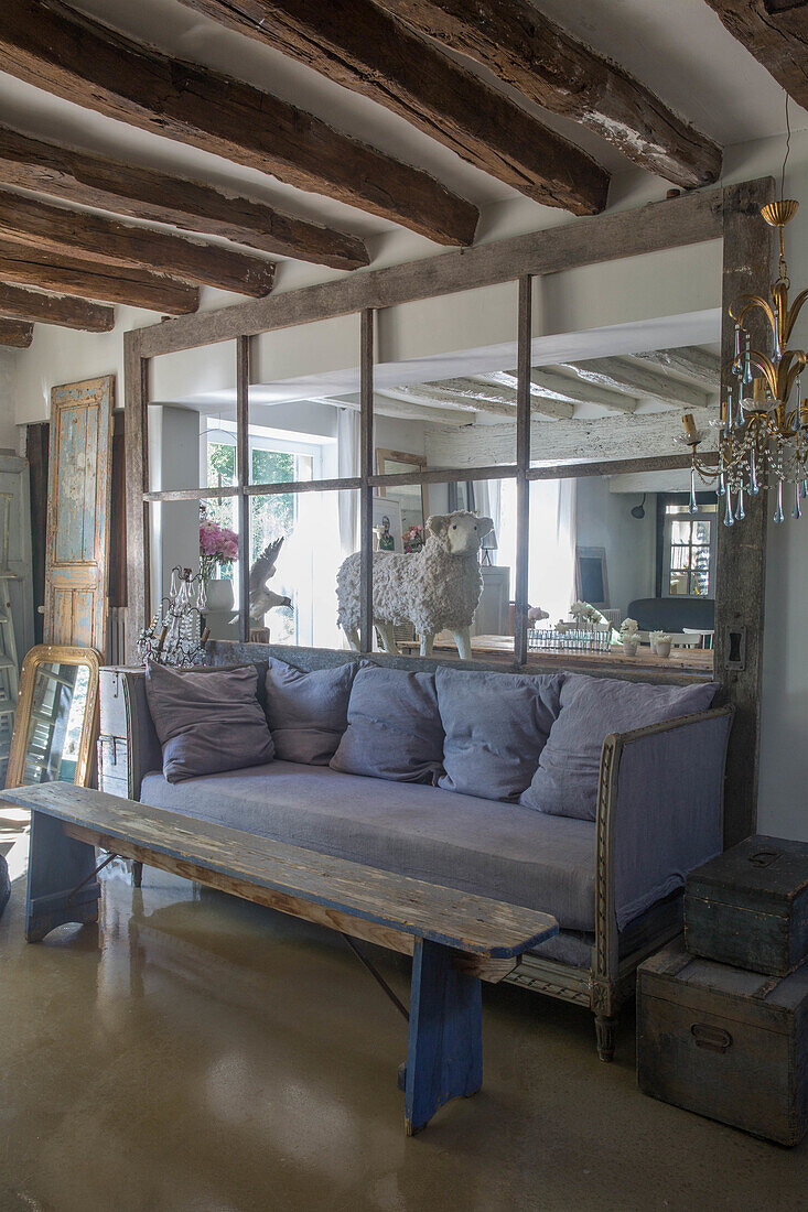 Seating area with blue upholstered sofa and rustic wooden bench with a view of the adjoining room