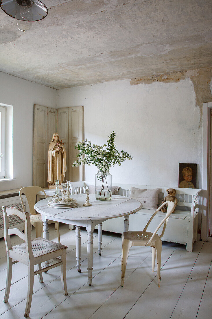 Round wooden table, white chairs and Madonna statue in rustic dining room