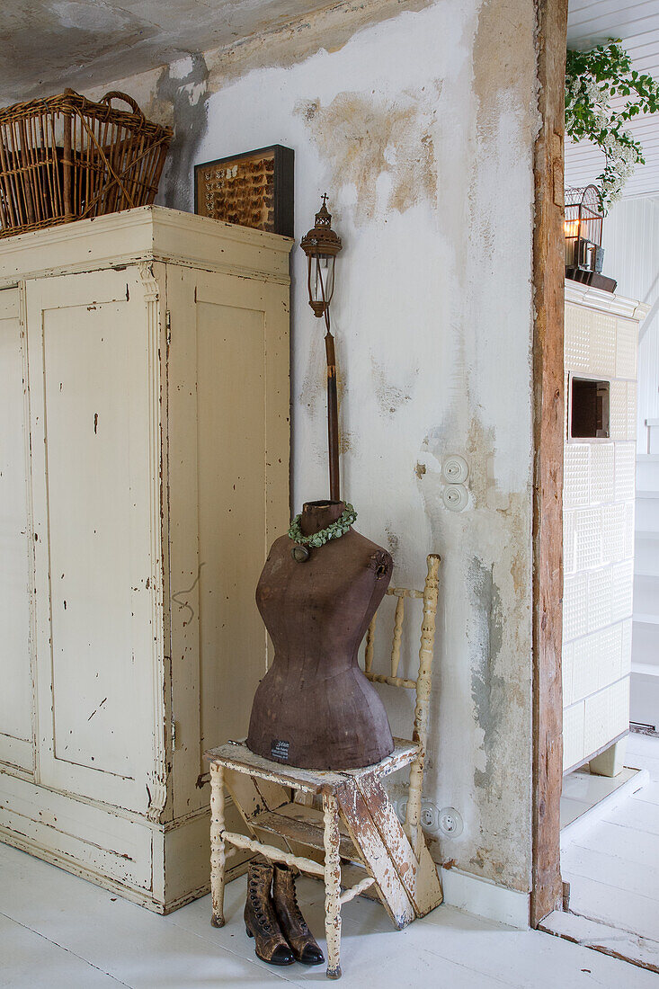 Decorated corner with dressmaker's dummy next to rustic wardrobe