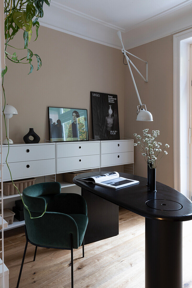 Modern home office with green velvet chair, black desk and wall art