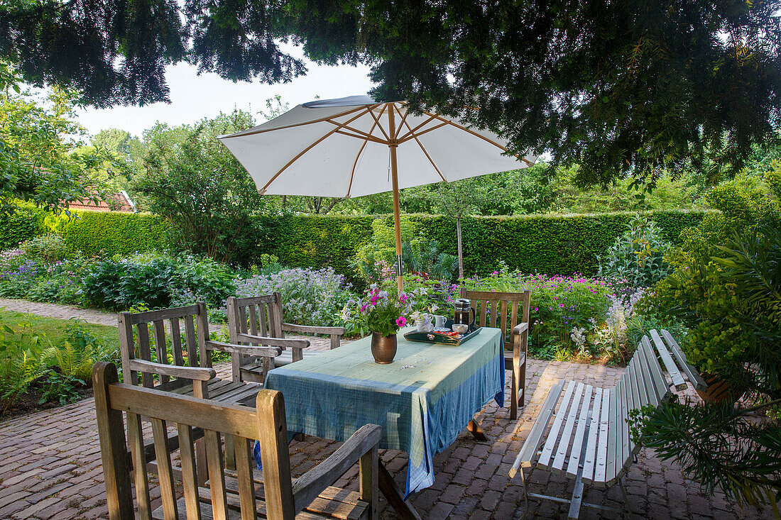 Garden seating area with wooden furniture and parasol in summer