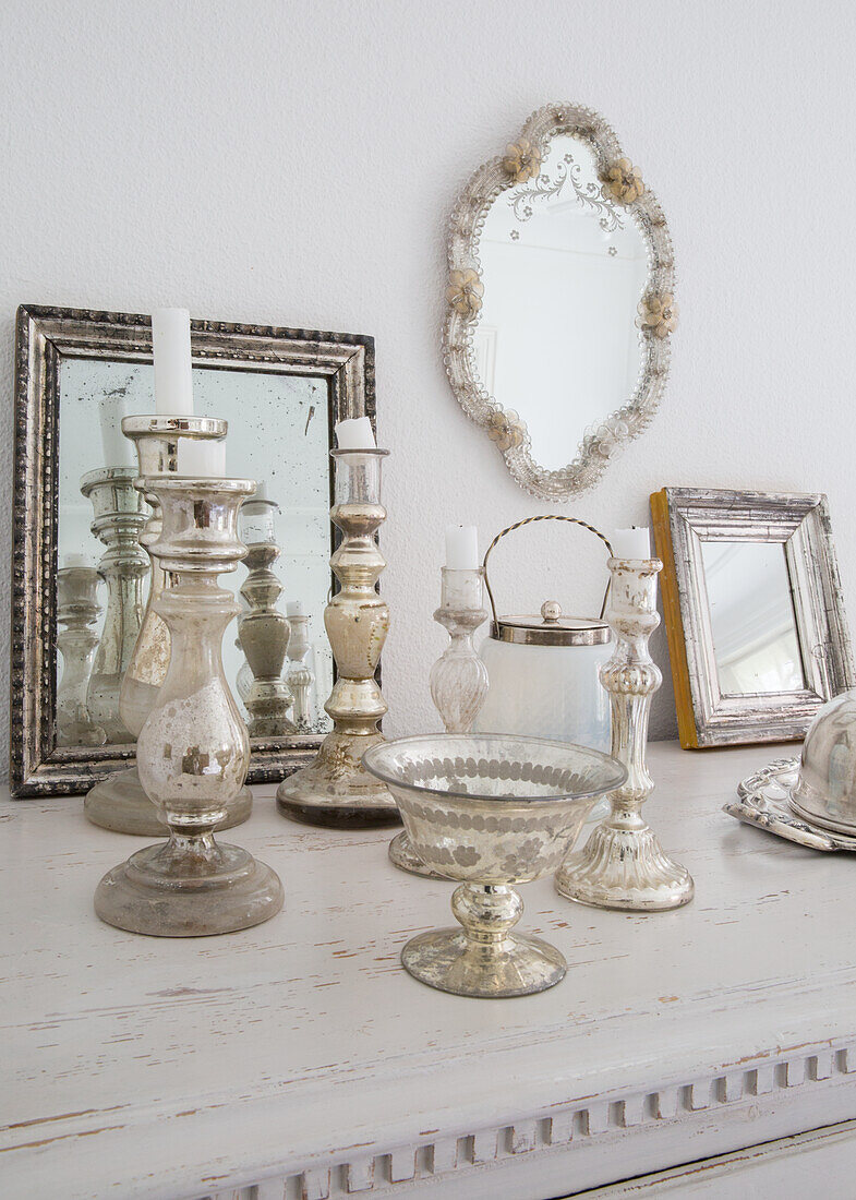 Antique silver candlesticks and mirrors on the dresser and on the wall