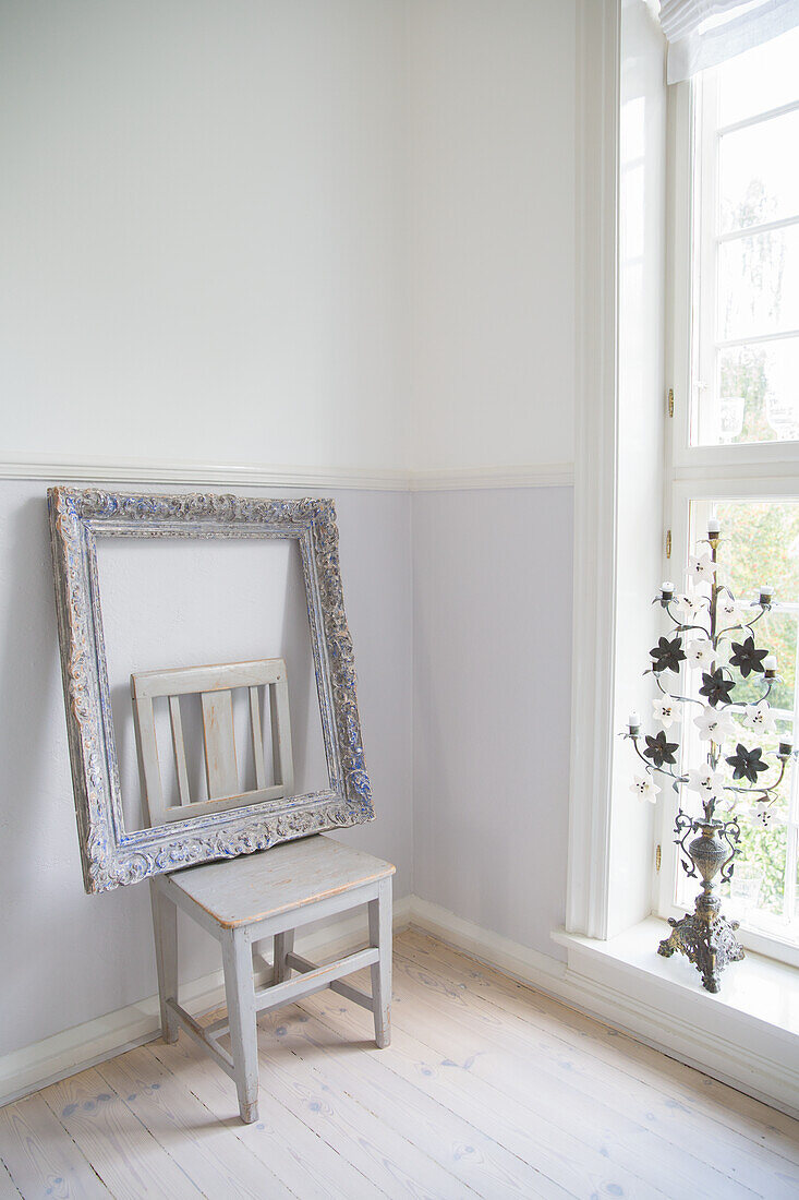 Quiet corner with empty picture frame on wooden stool next to window