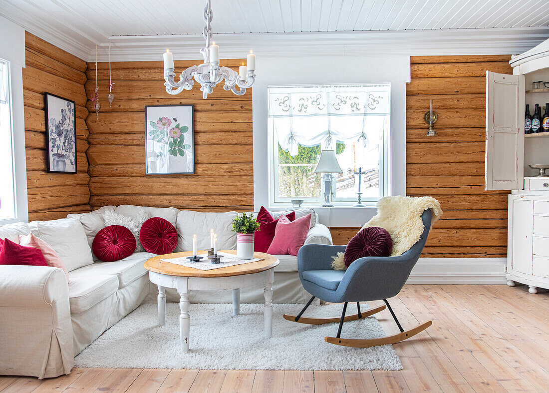 Gemütliches Wohnzimmer im Landhausstil mit Holzwänden, weißem Sofa und Schaukelstuhl