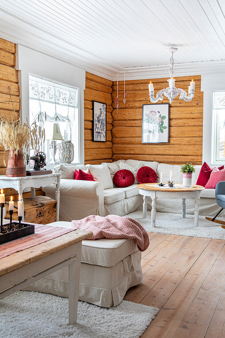 Living room with wooden walls and white sofa with red cushions