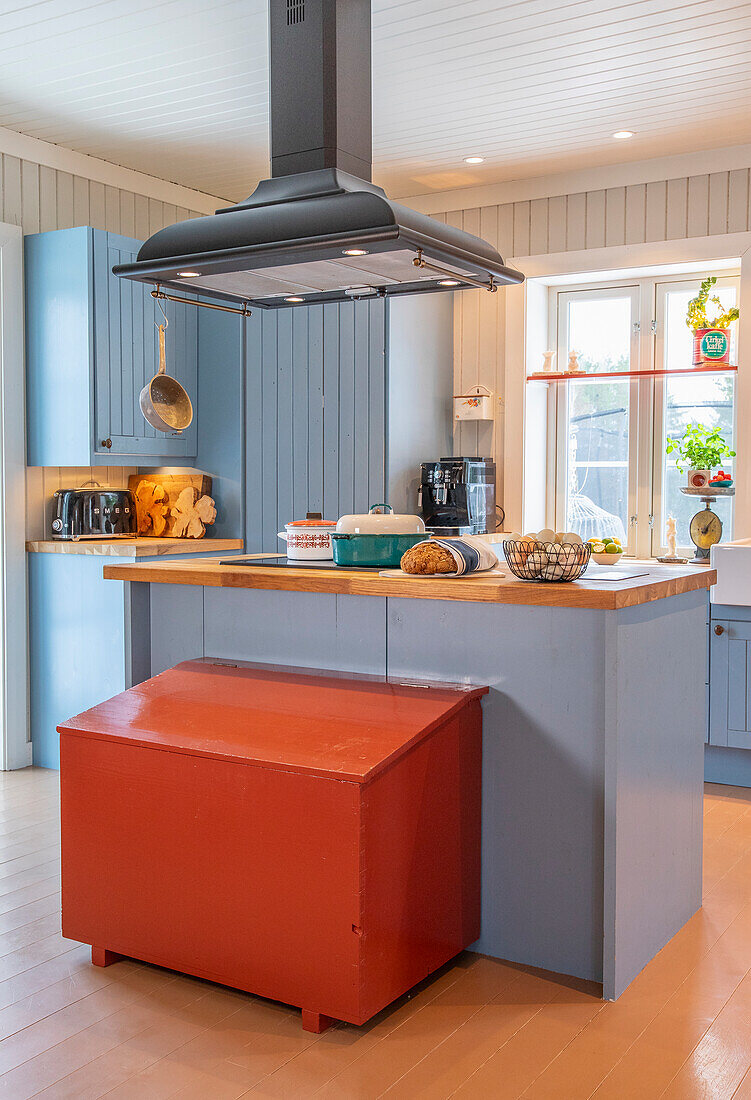 Kitchen in blue with red wooden chest and cooking island