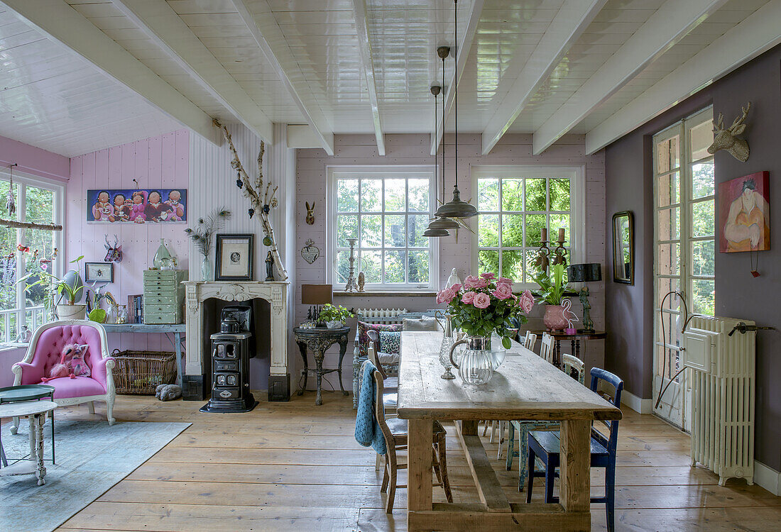 Open-plan dining area with solid wood table, pink accents and large windows