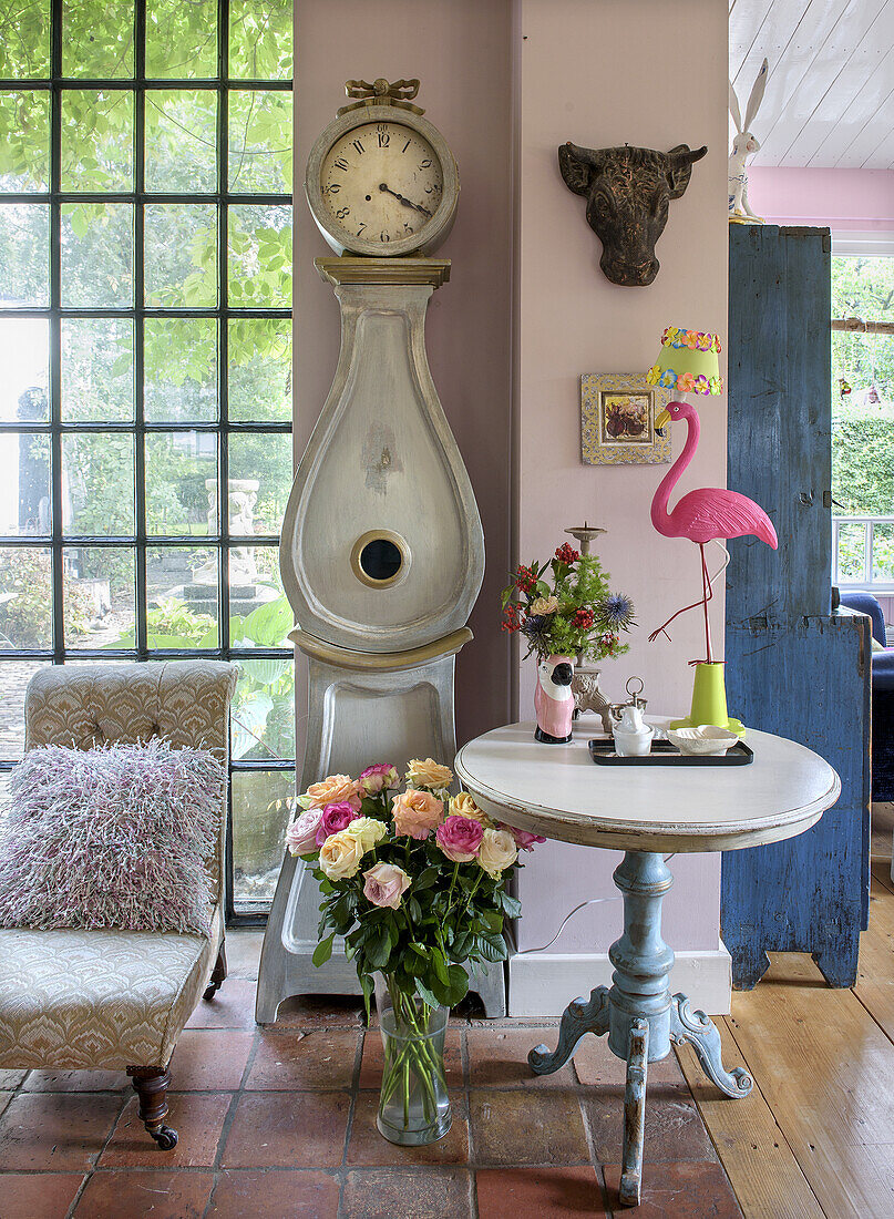 Country-style corner with grandfather clock, bouquets of flowers and decorative flamingo