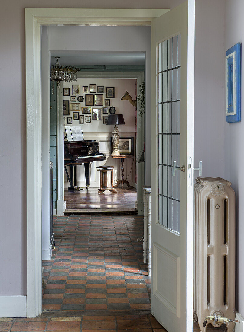 View through open door to room with piano and picture gallery on the wall