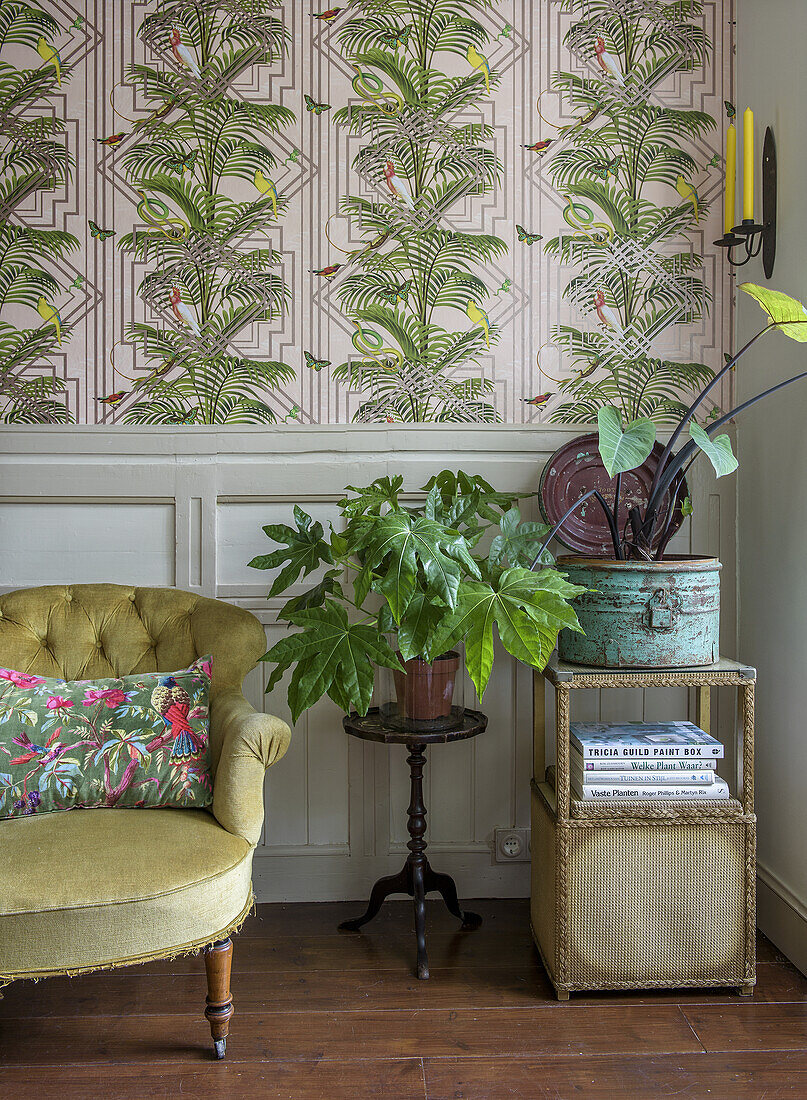 Mustard yellow armchair and potted plants in front of Art Nouveau wallpaper in the living room