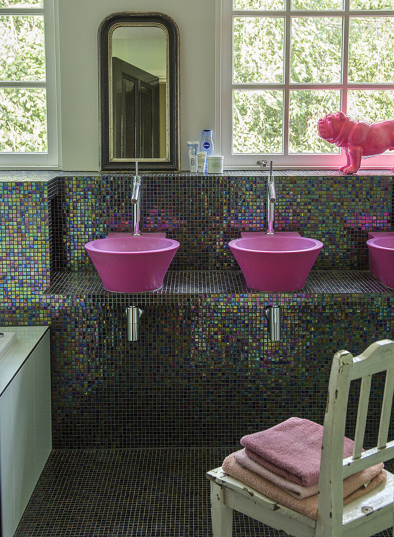 Bathroom with pink sinks and shimmering mosaic wall tiles