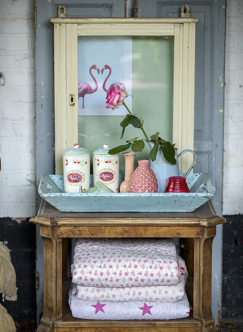 Vintage decorations and retro storage tins on a wooden tray in front of a flamingo art print