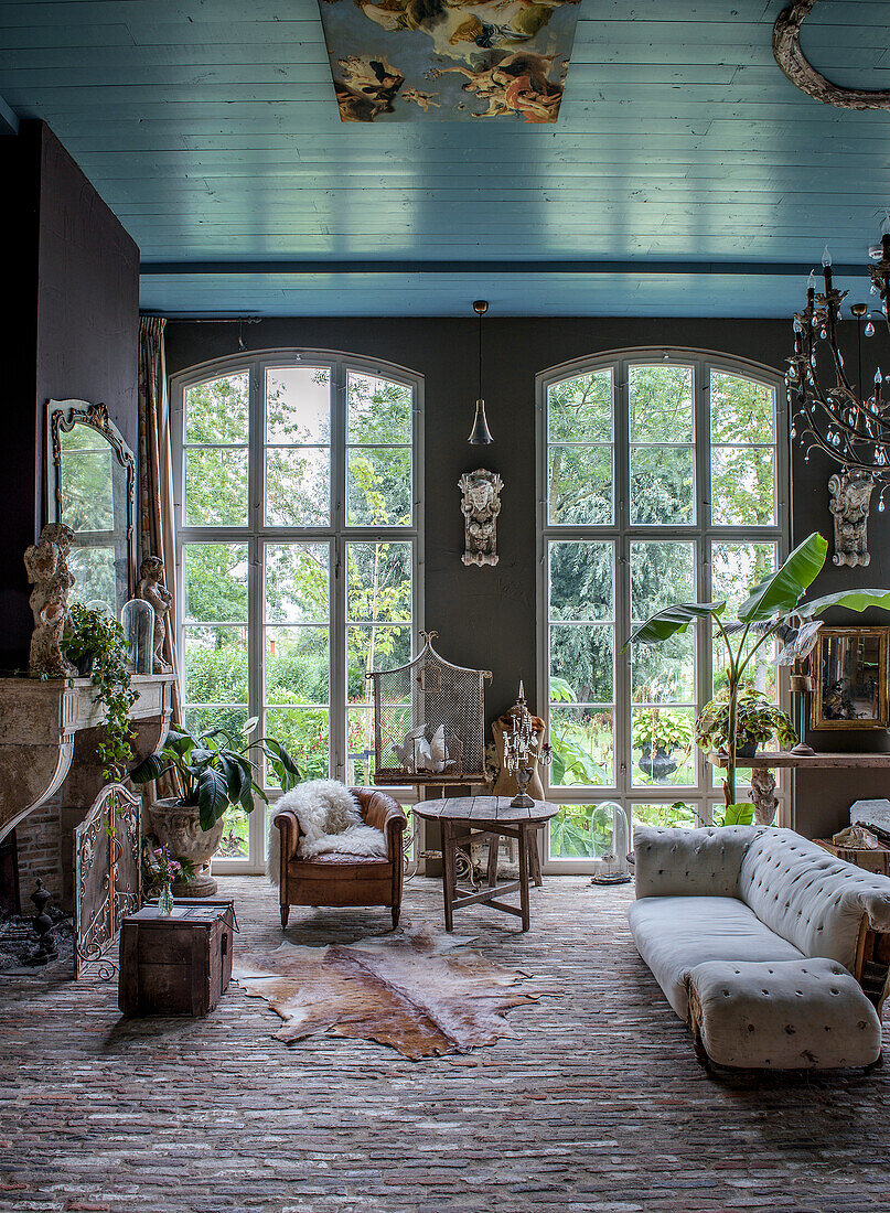 Living room with high windows, antique furniture and blue-painted ceiling