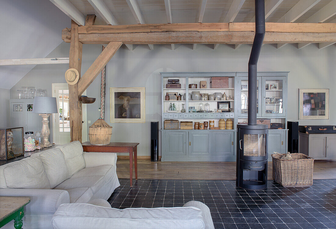 Open-plan living room with exposed wooden beams, wood-burning stove and rustic furnishings