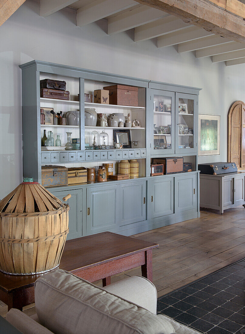 Vintage-Küchenschrank im Landhausstil mit antiken Kisten, Glasobjekten und Keramikgefässen