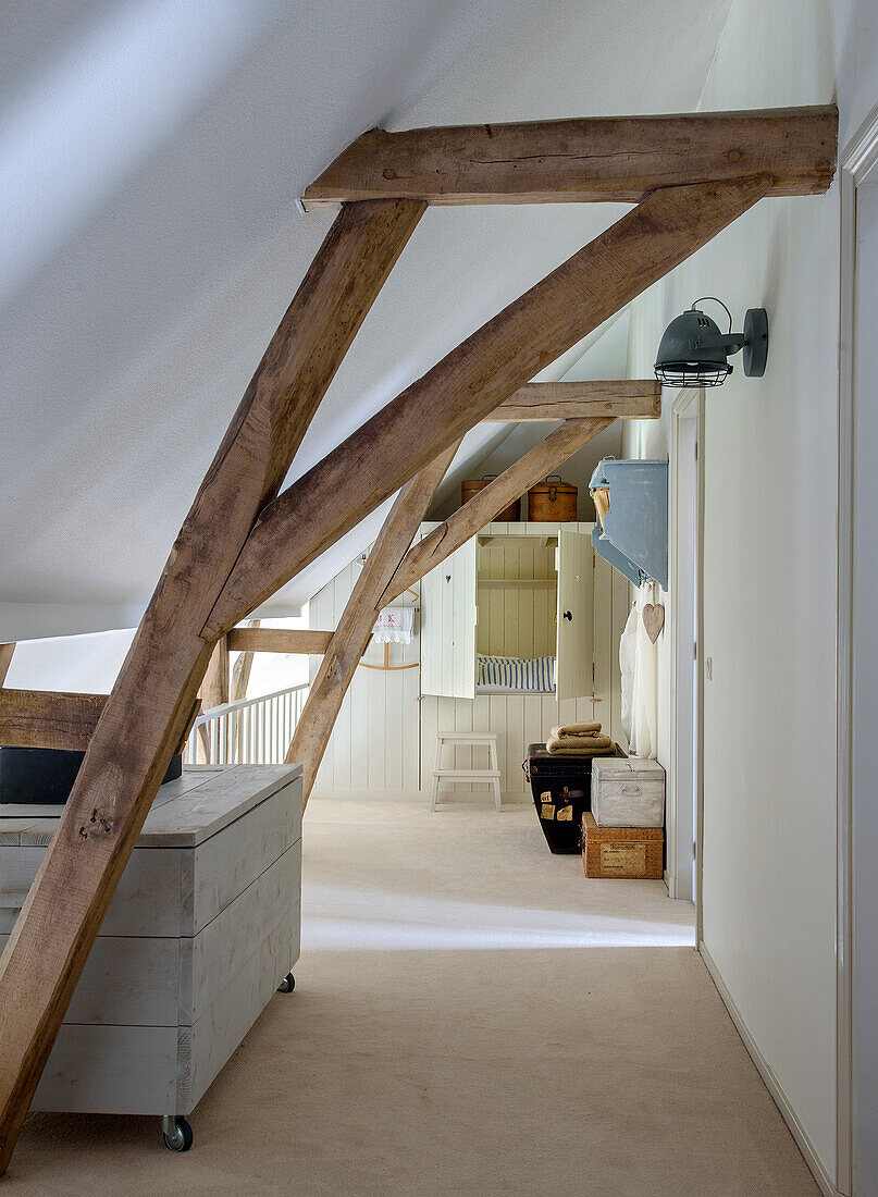 Attic hallway with exposed wooden beams and rustic furniture