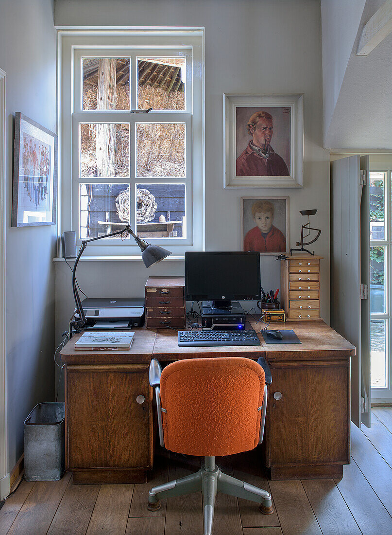 Vintage home office with antique wooden desk and orange office chair