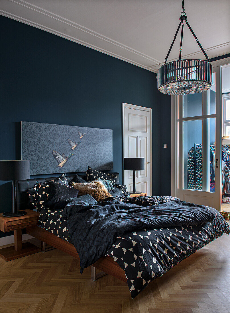 Bedroom with parquet flooring, dark blue wall colour and patterned textiles